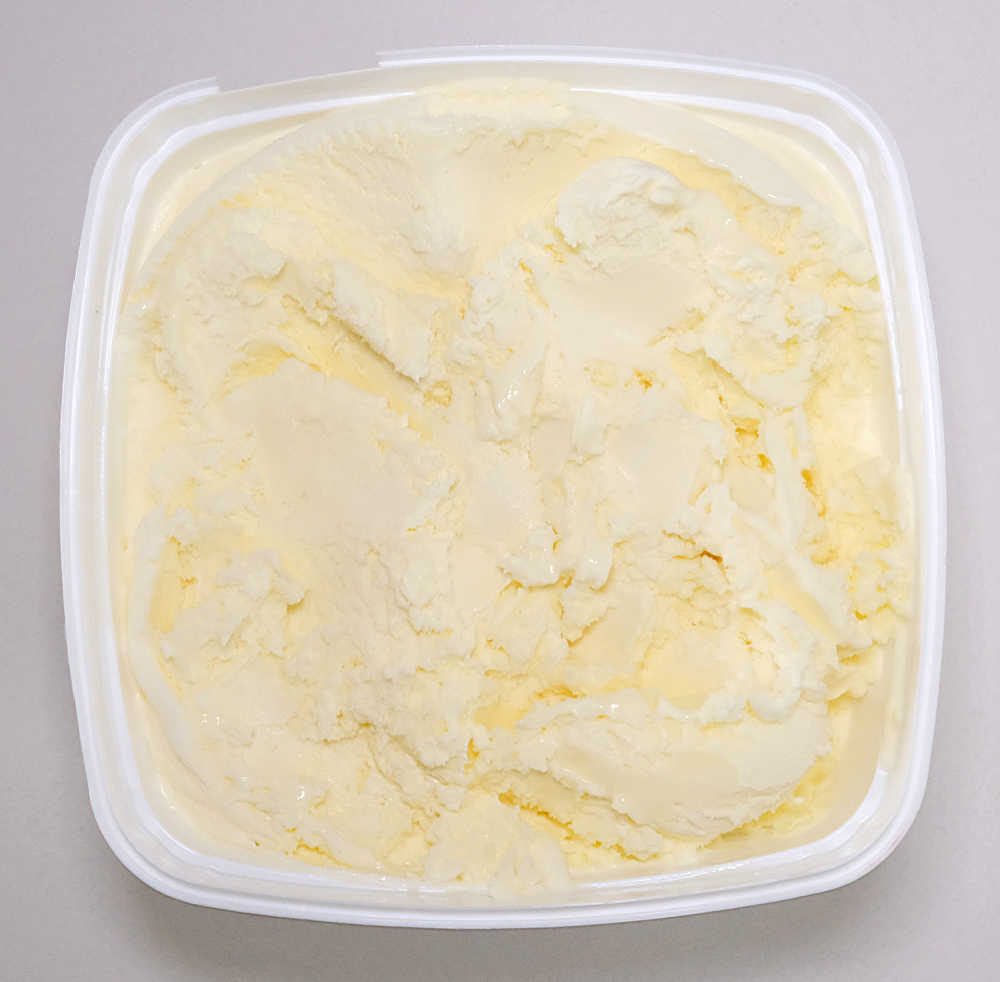 A top-down photo of a partly-eaten pack of Coles Vanilla Frozen Dessert 2L.