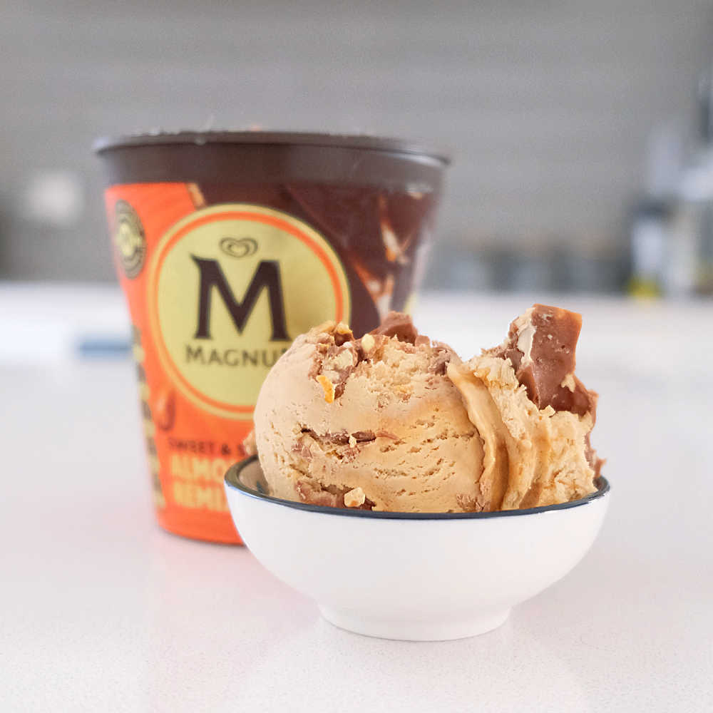 A bowl of Magnum Almond Remix Ice Cream with the container in the background.