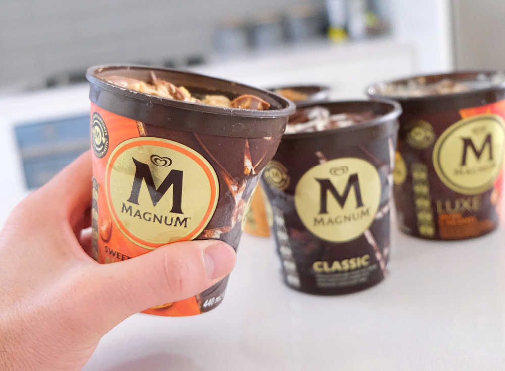 A hand holding a tub of Sweet and Salty Almond Remix 440ml.