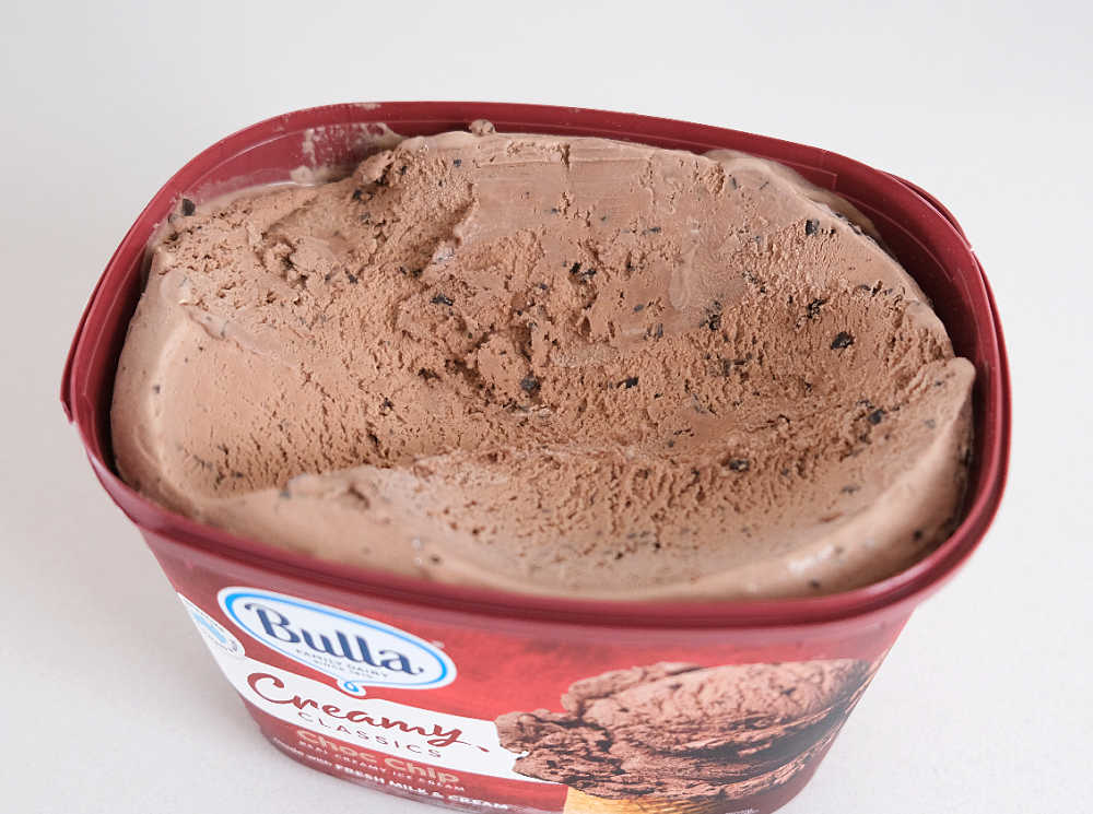 A partly scooped tub of Bulla Creamy Classics Choc Chip Ice Cream.