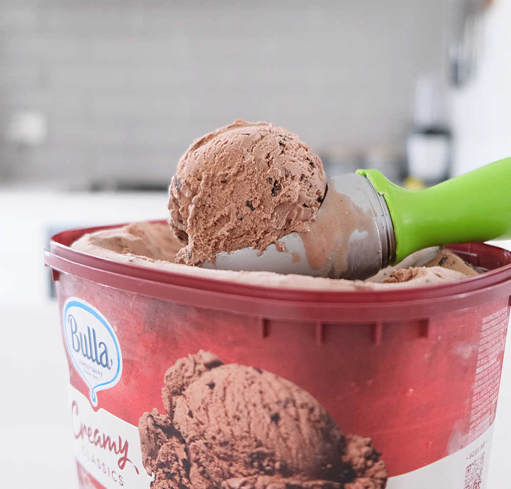 A scoop of Creamy Classics Chocolate Choc Chip resting on the container.